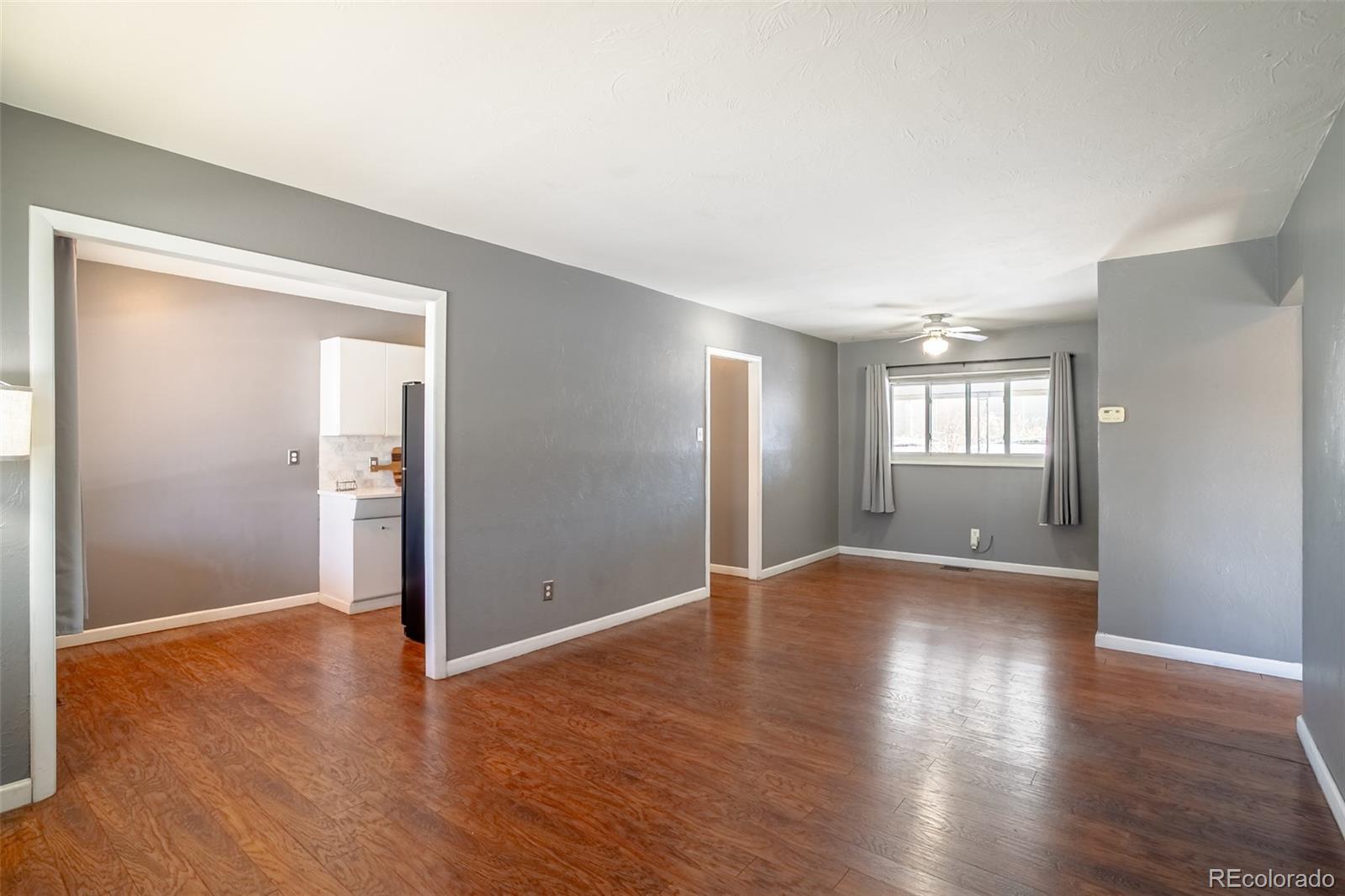 3016 South Grape Way Denver, CO 80222 - Photo 4 of 27 an empty room with wooden floor and windows