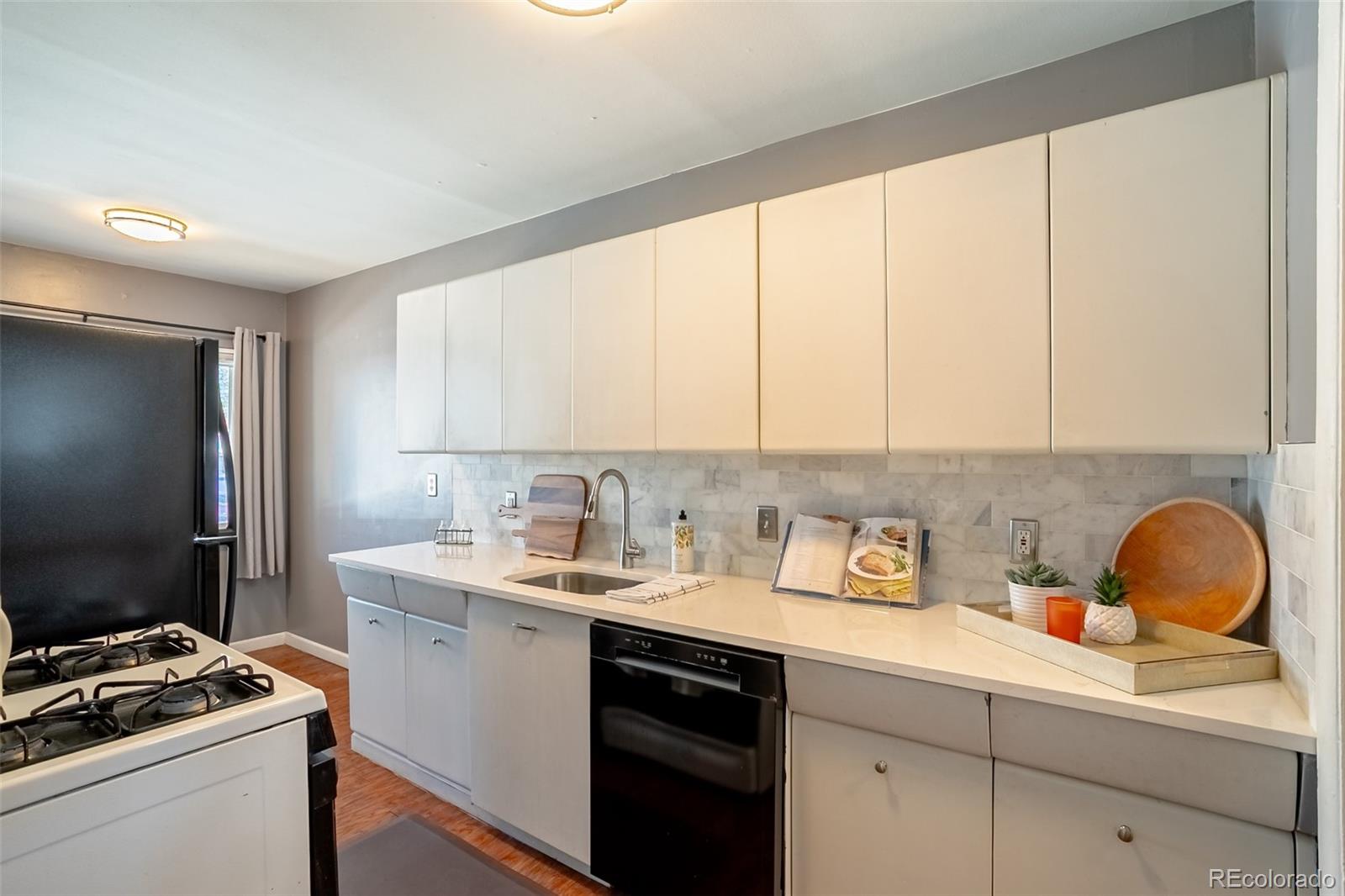 3016 South Grape Way Denver, CO 80222 - Photo 6 of 27 a kitchen with a sink cabinets and a window