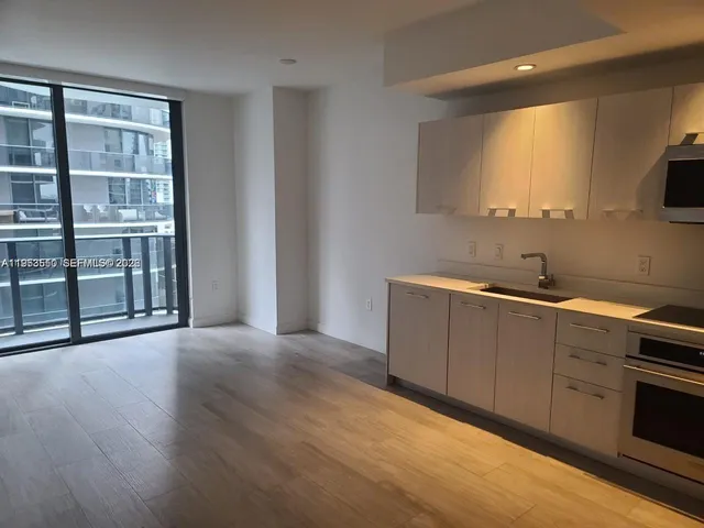 a view of a kitchen with wooden floor and electronic appliances