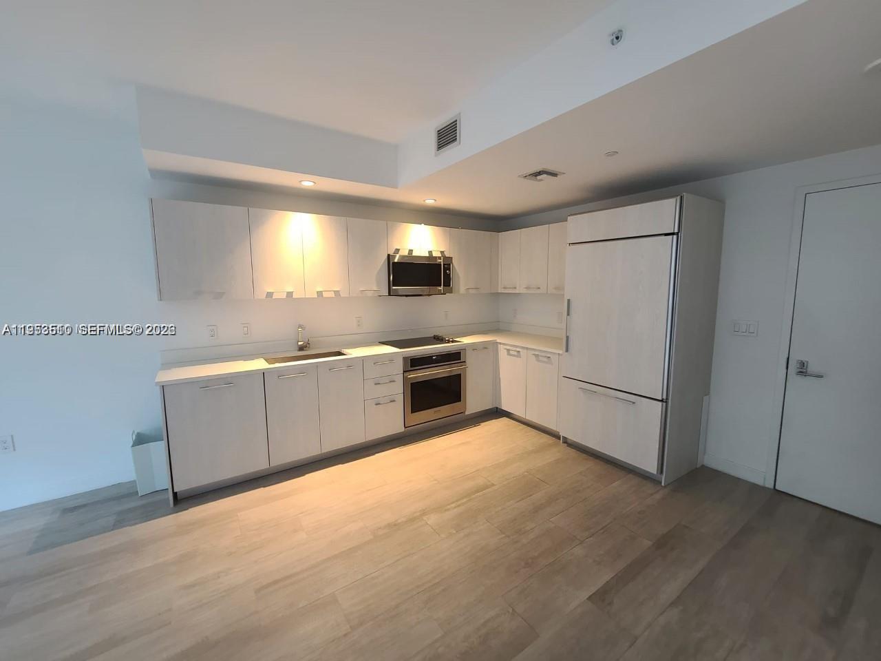 55 Southwest 9th Street, Unit 1502 Miami, FL 33130 - Photo 2 of 6 a large white kitchen with a sink stainless steel appliances and cabinets