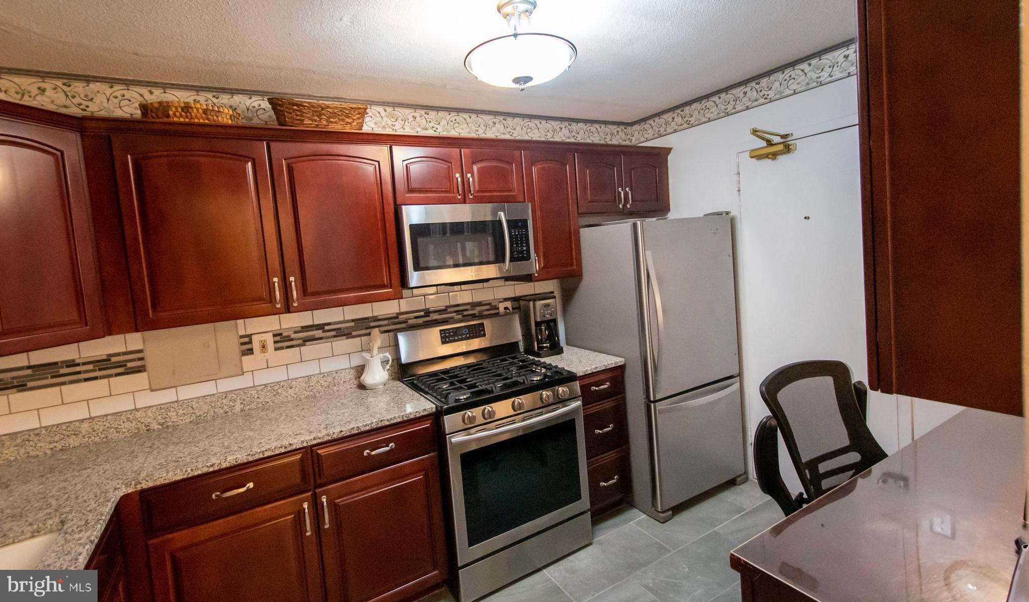 a kitchen with stainless steel appliances granite countertop a stove refrigerator and microwave