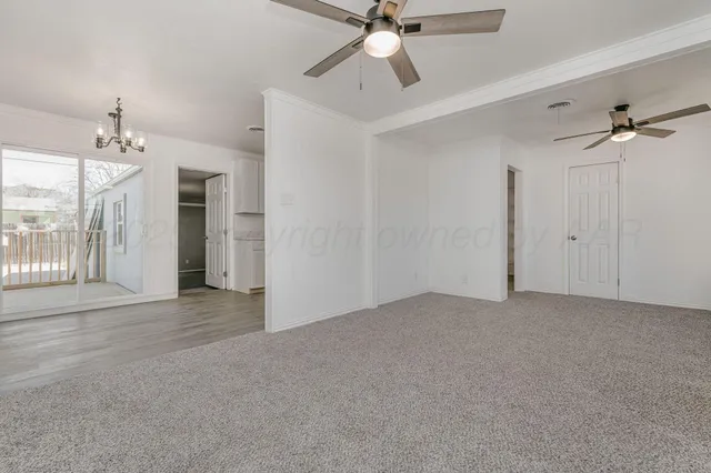 a view of a big room with a chandelier fan and windows