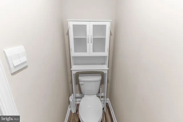 a white toilet sitting in a bathroom next to a wooden cabinet