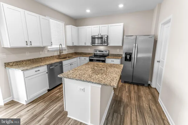 a kitchen with kitchen island granite countertop a sink appliances cabinets and counter space