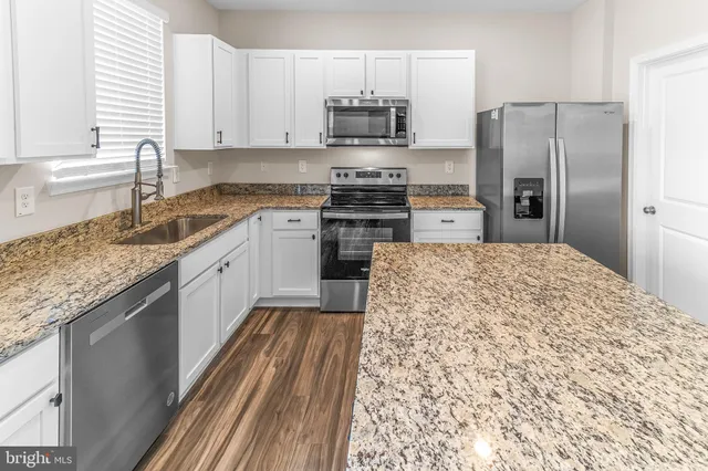 a kitchen with stainless steel appliances granite countertop a refrigerator sink and stove