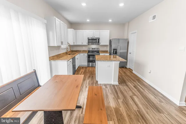 a open kitchen with kitchen island a stove a sink dishwasher and a refrigerator with wooden floor