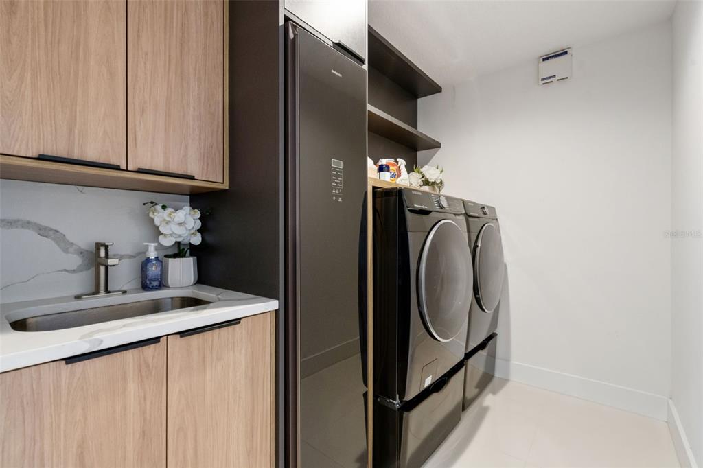908 Croton Road Celebration, FL 34747 - Photo 27 of 86 a utility room with stainless steel appliances granite countertop a sink and a washer dryer
