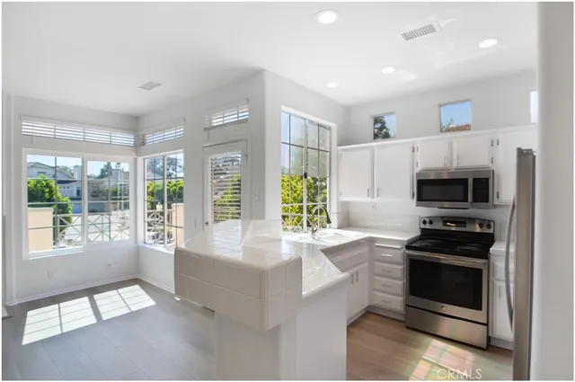 a large white kitchen with granite countertop a stove and a sink
