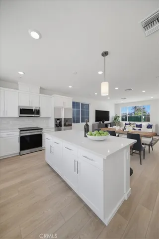 a large white kitchen with kitchen island a sink a stove a dining table and chairs