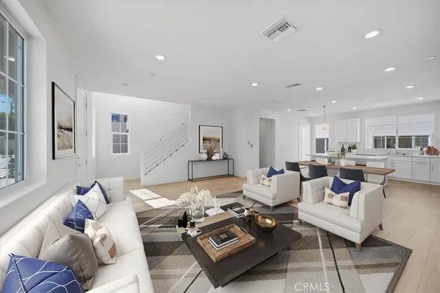 a living room with furniture couches and a dining table with wooden floor