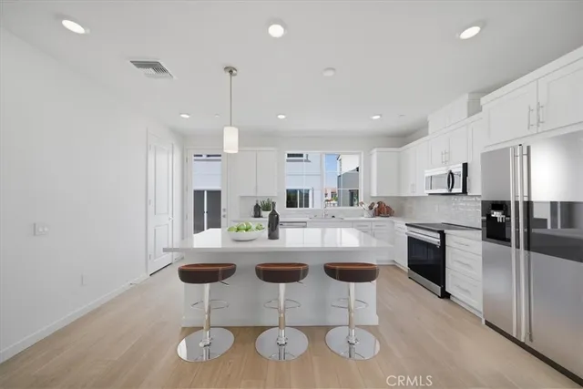 a kitchen with kitchen island white cabinets and stainless steel appliances