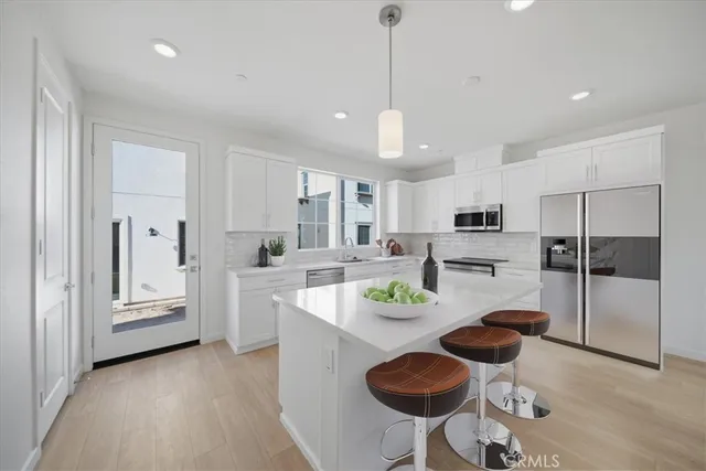 a kitchen with white cabinets and chairs