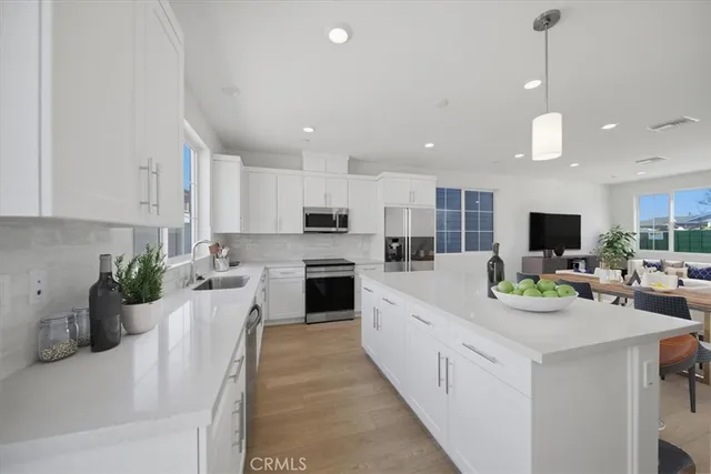 a kitchen with a sink dishwasher stove and white cabinets with wooden floor