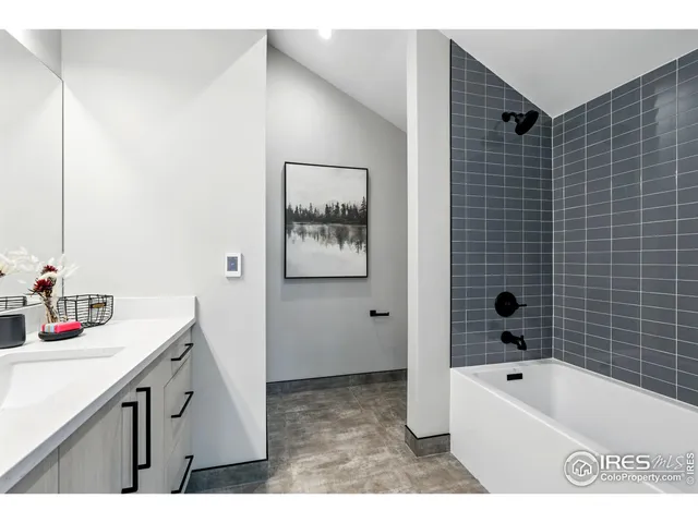 a bathroom with a tub sink vanity and mirror