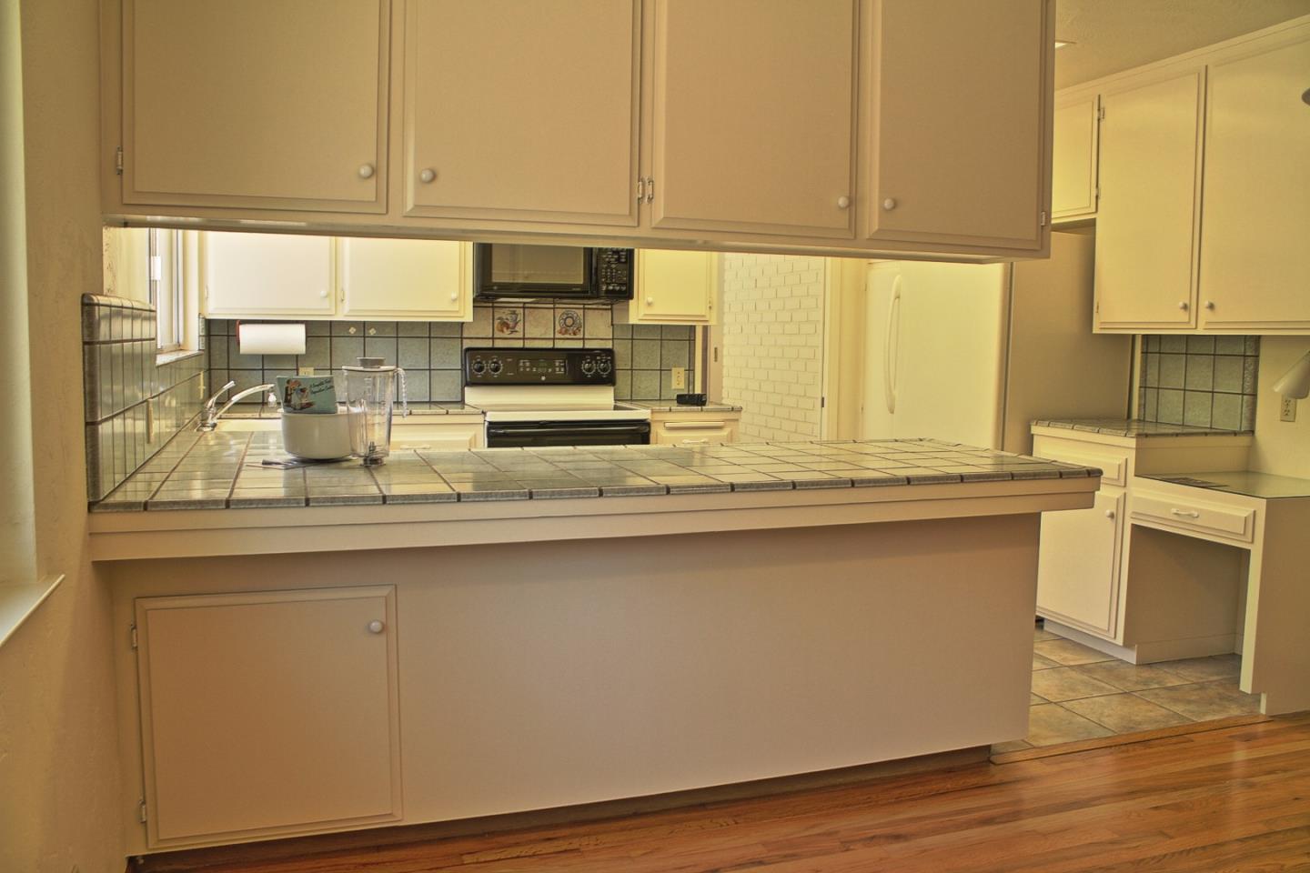 3035 Sloat Road Pebble Beach, CA 93953 - Photo 12 of 16 a kitchen with stainless steel appliances granite countertop a sink a stove and white cabinets with wooden floor