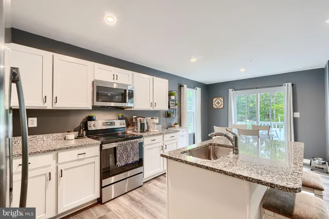 a kitchen with granite countertop a sink a stove and cabinets