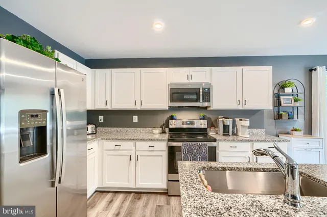a kitchen with stainless steel appliances granite countertop a refrigerator sink and stove