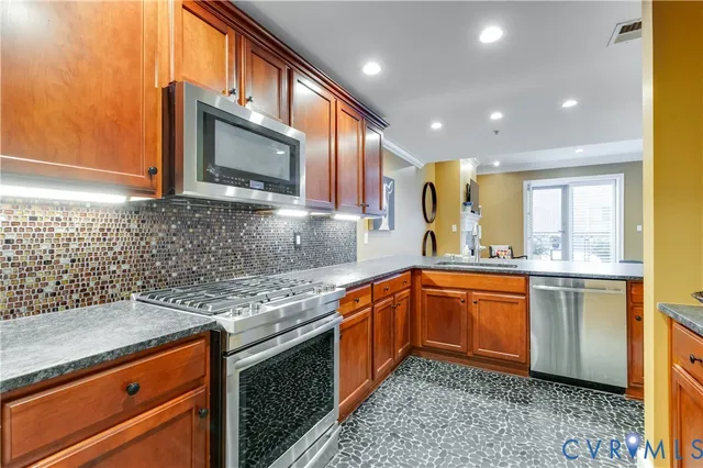 a kitchen with stainless steel appliances granite countertop a sink stove and cabinets