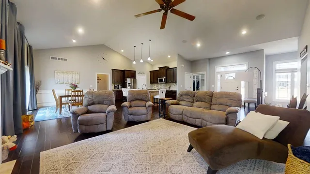a living room with furniture kitchen view and a wooden floor