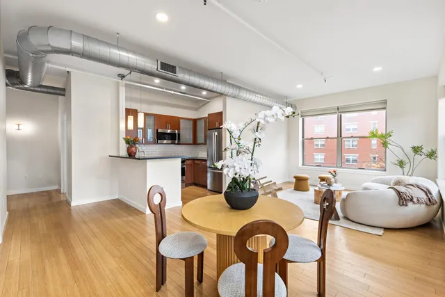 a kitchen with stainless steel appliances granite countertop a stove a refrigerator a dining table and chairs with wooden floor