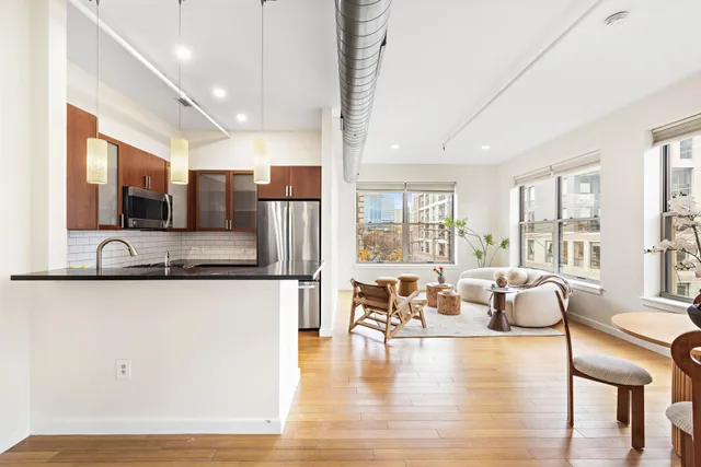 a large living room with stainless steel appliances kitchen island granite countertop wooden floor and large window