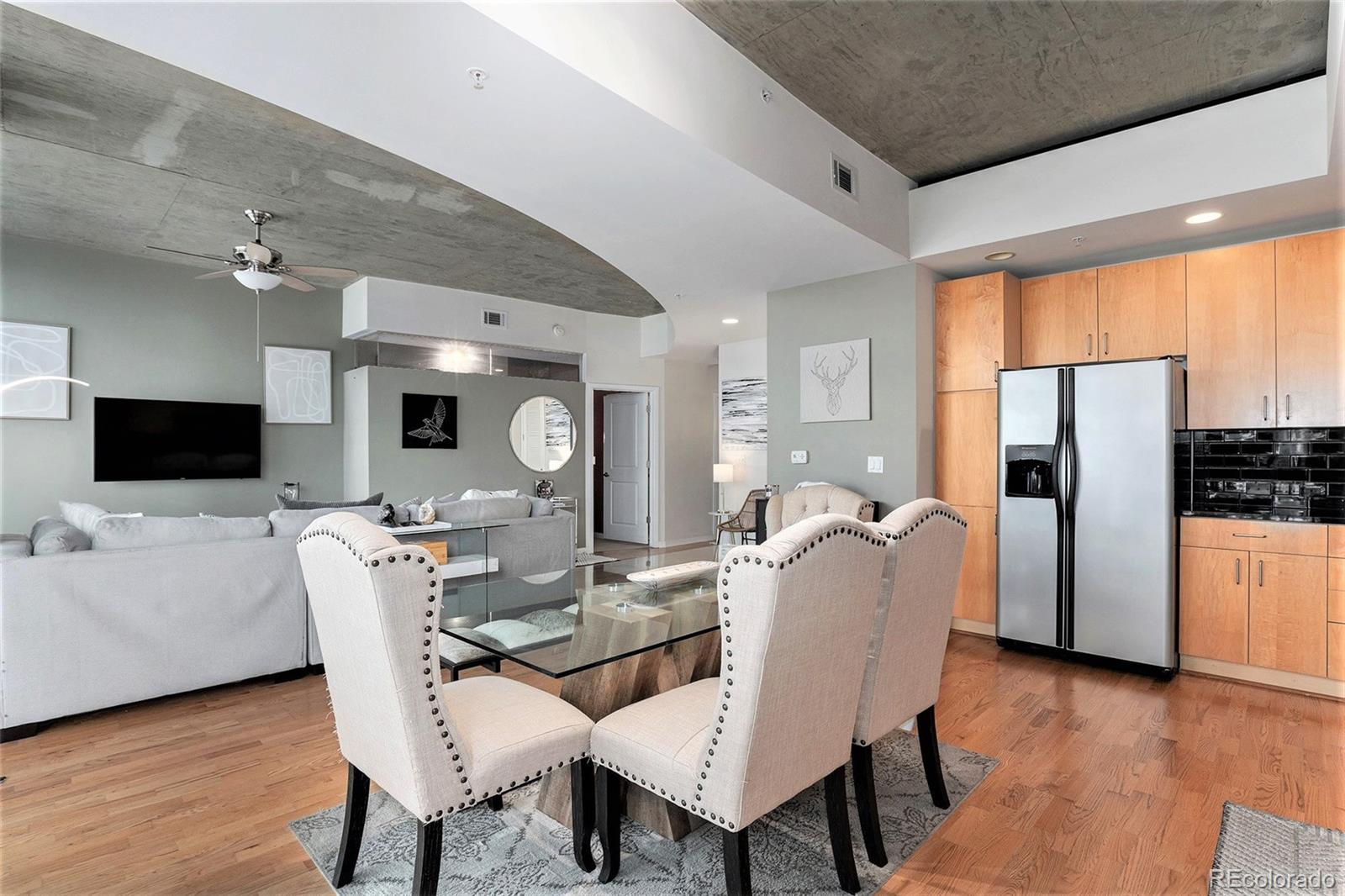 1700 Bassett Street, Unit 903 Denver, CO 80202 - Photo 13 of 31 a dining room with furniture a rug a flat screen tv a rug and a painting