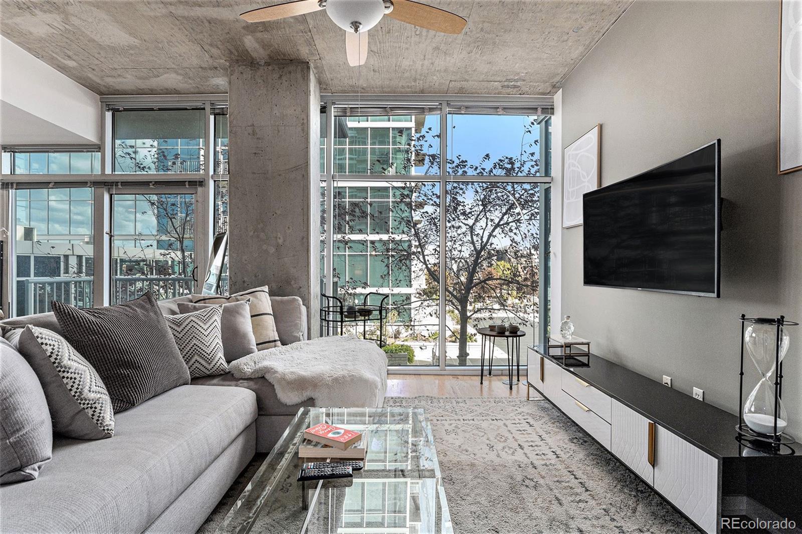 1700 Bassett Street, Unit 903 Denver, CO 80202 - Photo 7 of 31 a living room with furniture a flat screen tv and a floor to ceiling window