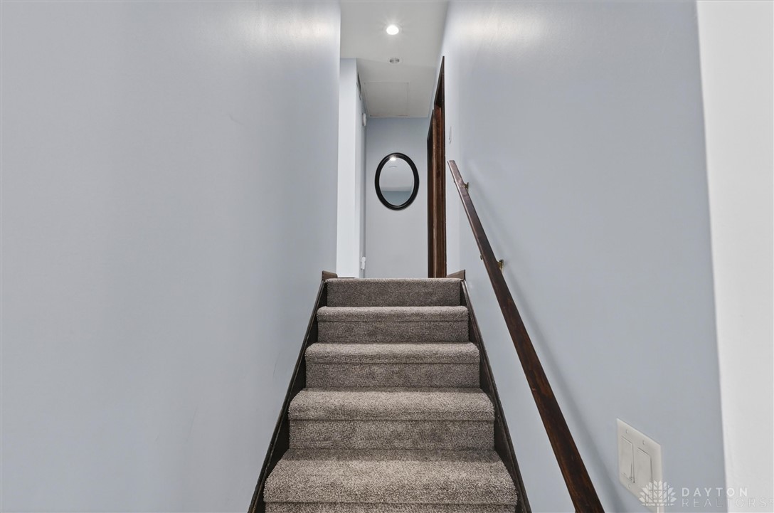 2165 Stewart Road Xenia, OH 45385 - Photo 28 of 59 This interior staircase features carpeted treads and a wooden handrail, leading to an upper landing.