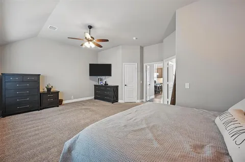a bedroom with a bed a flat screen tv and a chandelier