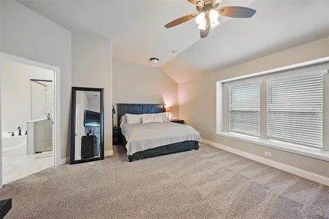 a bedroom with a large bed and a chandelier fan
