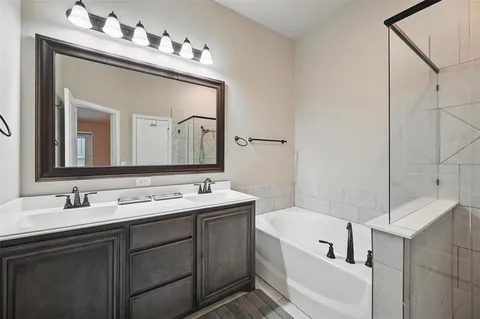 a bathroom with a double vanity sink mirror and bathtub