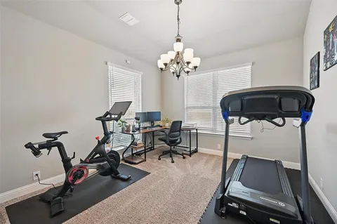 a room with gym equipment and wooden floor