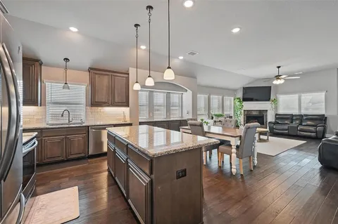 a kitchen with stainless steel appliances granite countertop a sink a stove and a wooden floors