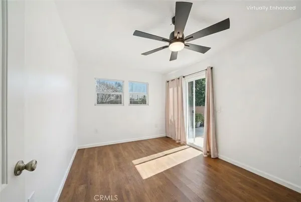 an empty room with wooden floor fan and windows