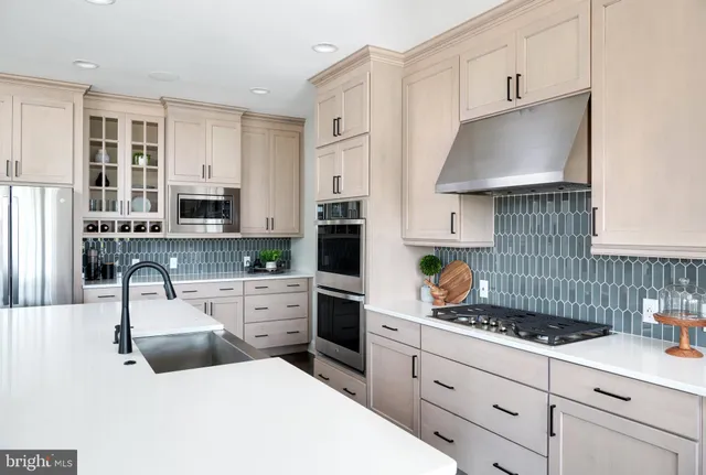 a kitchen with stainless steel appliances a stove a sink a oven a table and chairs