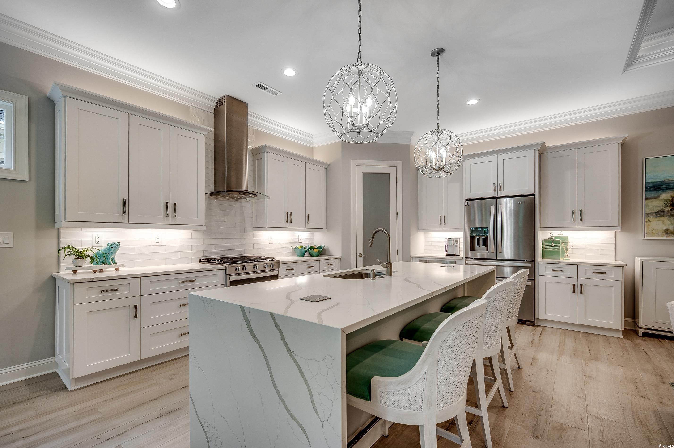 8404 Cape Dutch Loop Myrtle Beach, SC 29572 - Photo 11 of 40 Kitchen with a kitchen bar, appliances with stainless steel finishes, wall chimney exhaust hood, pendant lighting, and tasteful backsplash