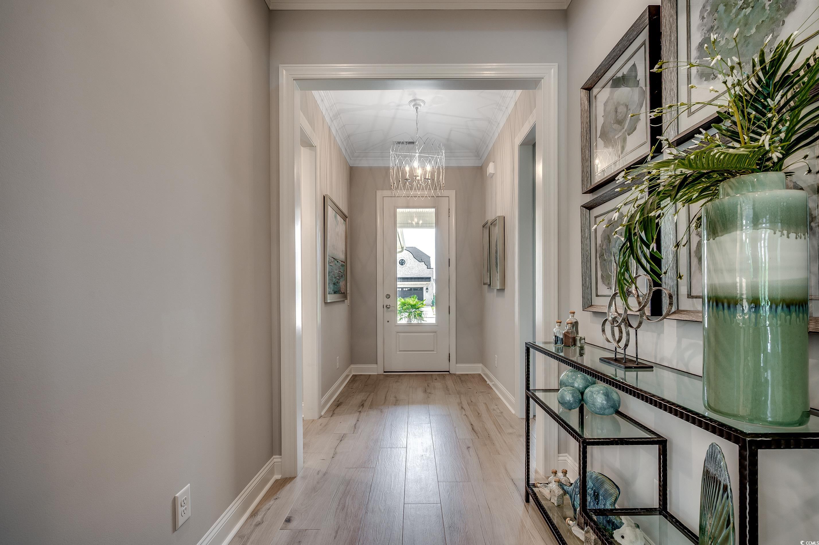 8404 Cape Dutch Loop Myrtle Beach, SC 29572 - Photo 4 of 40 Doorway featuring wood finished floors, a chandelier, and crown molding