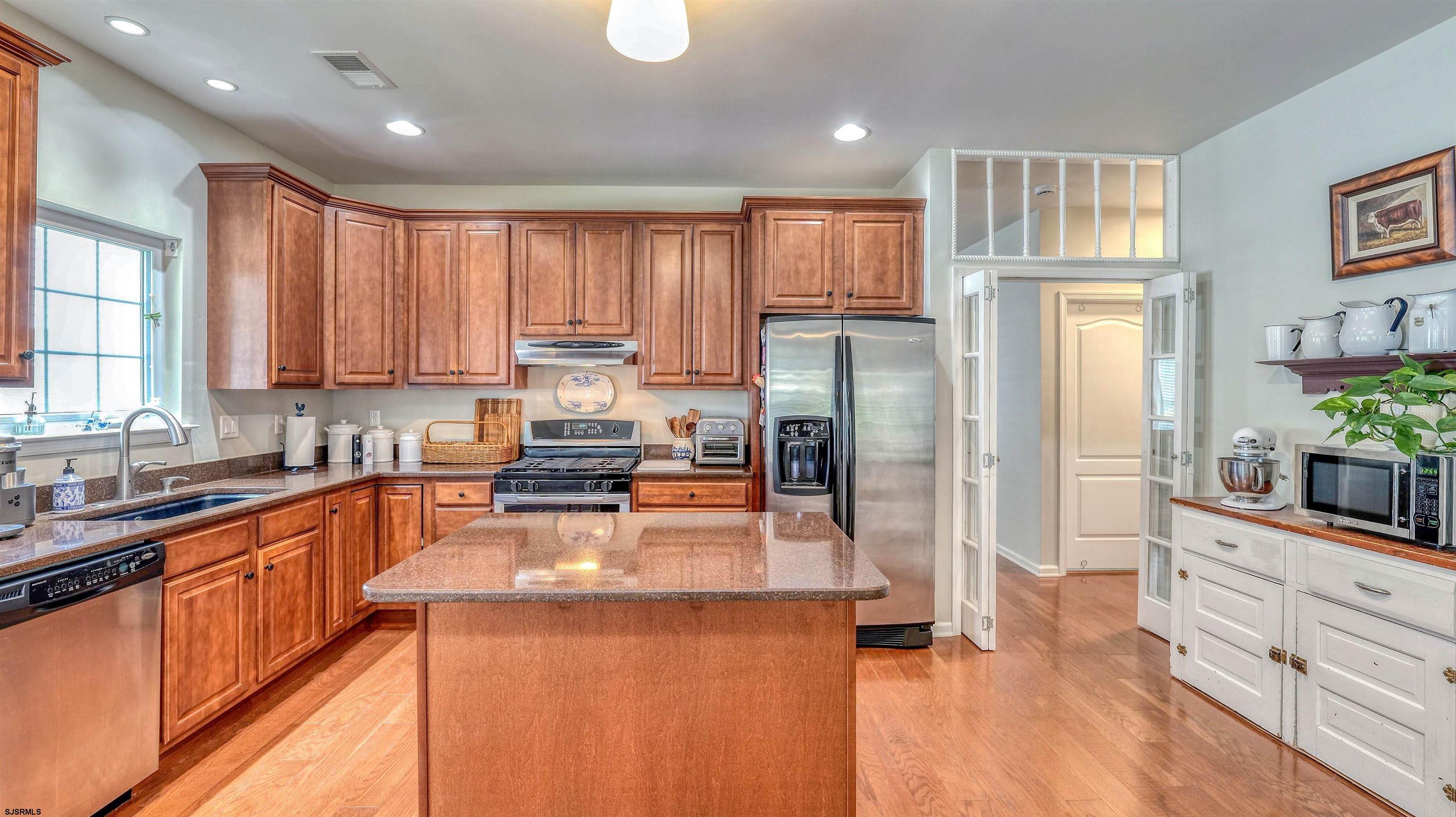 243 Lily Road Egg Harbor Township, NJ 08234 - Photo 8 of 29 a kitchen with stainless steel appliances granite countertop a refrigerator a stove a sink dishwasher and wooden cabinets with wooden floor