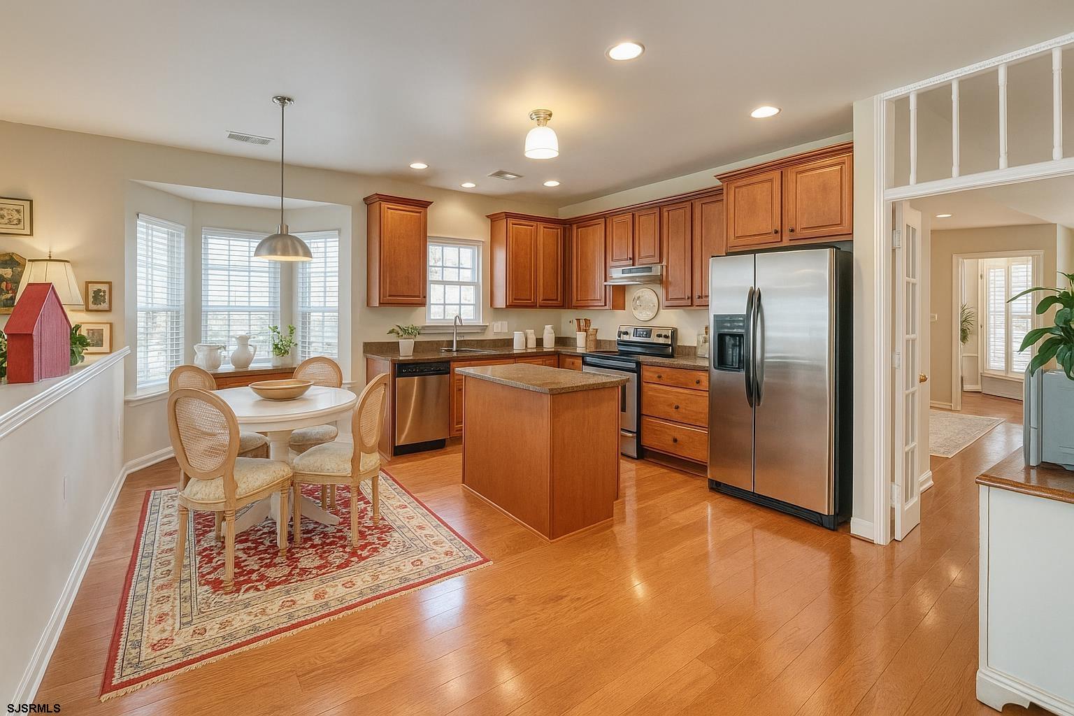 243 Lily Road Egg Harbor Township, NJ 08234 - Photo 9 of 29 a kitchen with stainless steel appliances granite countertop a stove top oven a refrigerator a sink a dining table and chairs with wooden floor