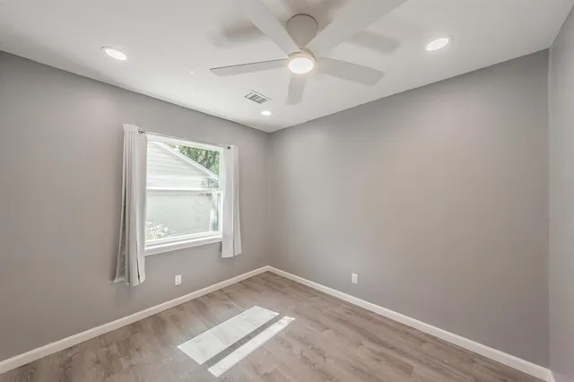 an empty room with a window and a fan