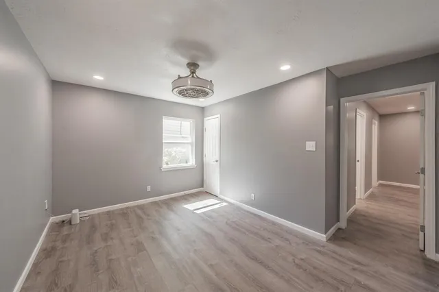 a view of an empty room with wooden floor and a window