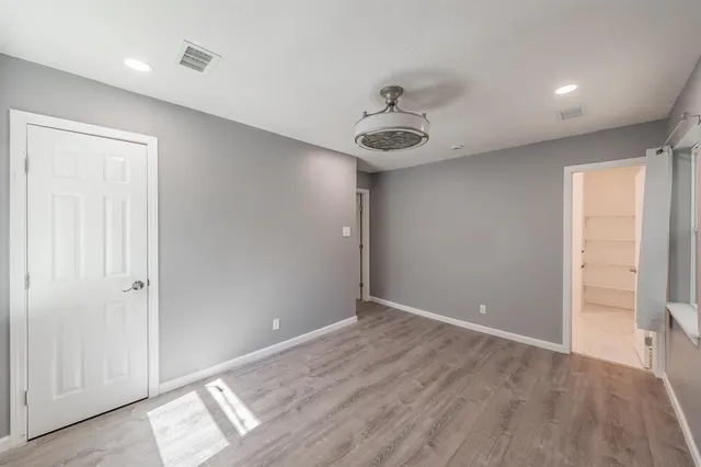 an empty room with wooden floor and hallway