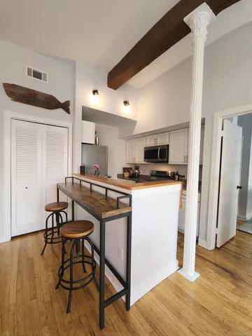 a kitchen with stainless steel appliances a microwave a stove a refrigerator and wooden floor