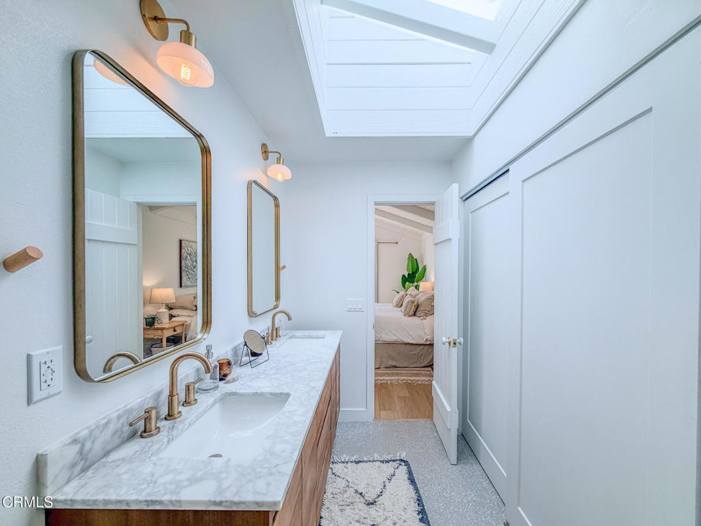 4954 Dolphin Way Oxnard, CA 93035 - Photo 32 of 40 a en suite bathroom with a granite countertop sink and a mirror