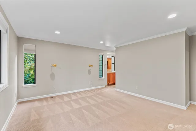 a view of an empty room with wooden floor and windows