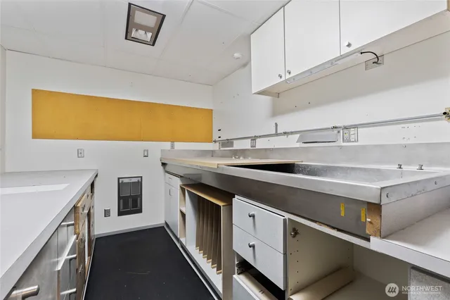 a kitchen with stainless steel appliances a sink dishwasher a stove and white cabinets with wooden floor