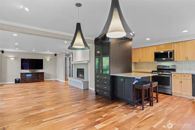 a living room with stainless steel appliances furniture a flat screen tv and kitchen view