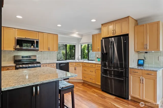 a kitchen with granite countertop a refrigerator a stove a sink a window and wooden cabinets