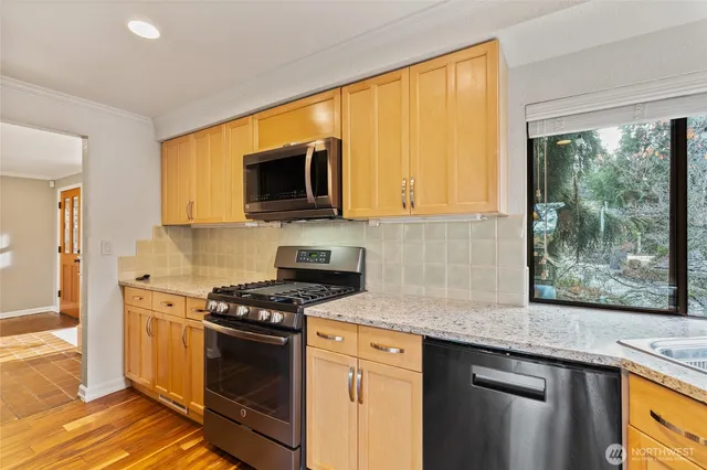 a kitchen with stainless steel appliances granite countertop a stove a sink and a microwave