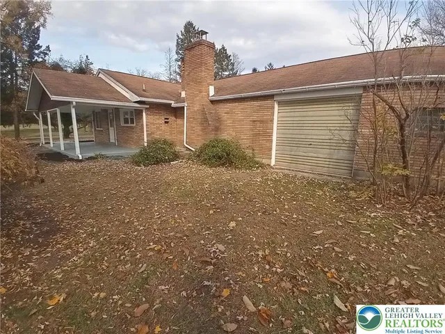 a front view of house with yard and trees in the background